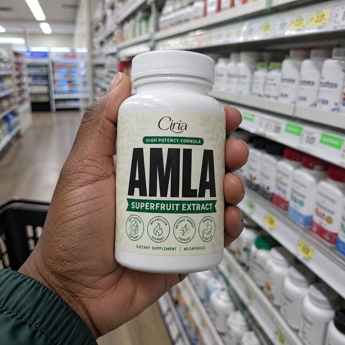 A hand holding a bottle of Ciria Amla Superfruit Extract in a pharmacy supplement aisle